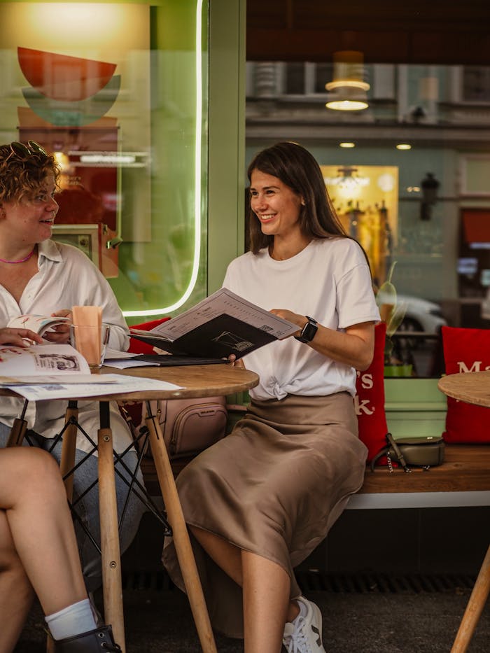 Two women enjoying a casual conversation at a trendy café, sharing moments of laughter.